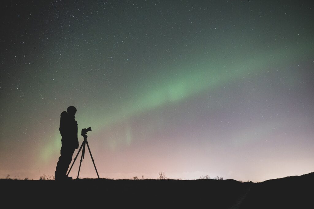Man with camera on a tripod adjusting Camera settings in astrophotography